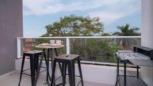 Ein Balkon mit Tisch, zwei Hocker und einem Grill.
