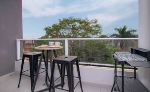 A balcony with a table, two stools, and a grill. - Corporate Stays First Living - 205 (Asunción)
