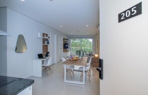 A modern kitchen with a dining area, a laptop on the desk, and a number 205 sign. - Corporate Stays First Living - 205 (Asunción)