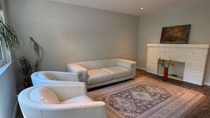 A modern living room with a white sofa set, a patterned rug, and a fireplace.