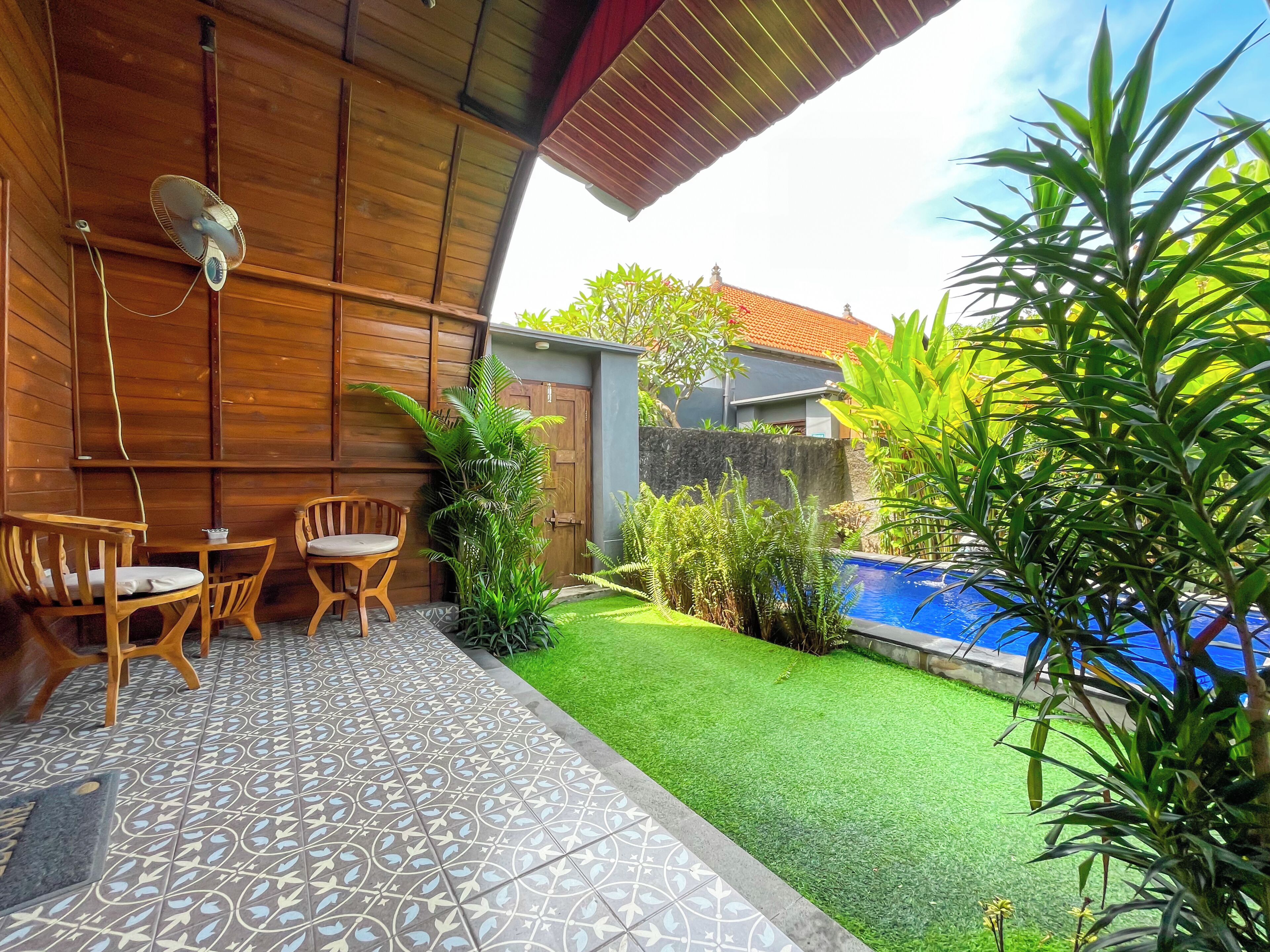 A patio with a wooden ceiling, a pool, and a small garden area.