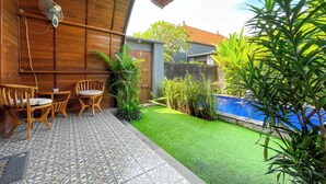 Eine Terrasse mit Holzboden, einem Pool und einer kleinen Gartenanlage.