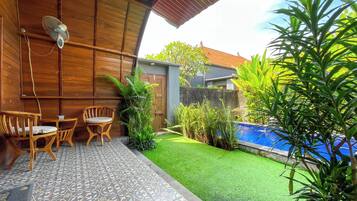 A patio with a wooden ceiling, a pool, and a small garden area.