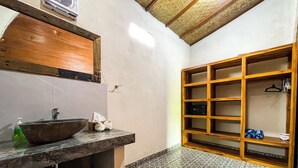 Ein Badezimmer mit einem Holzkosmetikschrank, einem großen Spiegel, einem Waschbecken und Fliesenboden.