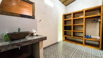 A bathroom with a wooden vanity, a large mirror, a sink, and a tiled floor.