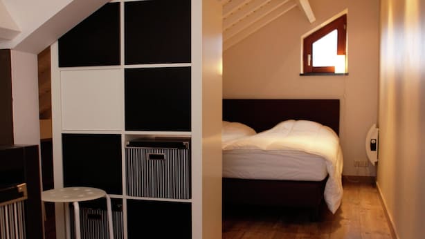 Um quarto com cama, uma mesinha e um armário embutido.