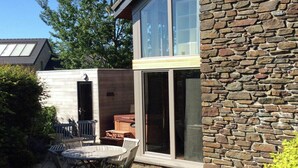 Uma casa moderna com fachada de pedra, uma grande porta de vidro e um pátio com móveis de exterior.