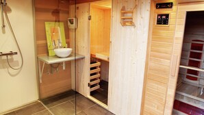 Uma sala de sauna de madeira com porta de vidro, uma pia e um painel de controle.