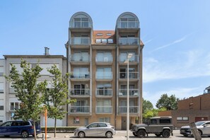 A multi-story residential building with balconies, a parking lot, and a clear sky. - 1 bedroom accommodation in Nieuwpoort (Nieuwpoort)