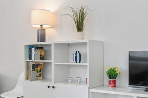 A white bookshelf with books, a lamp, a plant, and a TV. - 1 bedroom accommodation in Nieuwpoort (Nieuwpoort)