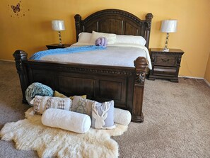 Un dormitorio con una cama de madera, dos mesitas de noche con lámparas, una alfombra mullida y una decoración en la pared.