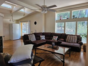 Un salon spacieux avec un grand canapé d’angle, une table basse et un ventilateur de plafond.