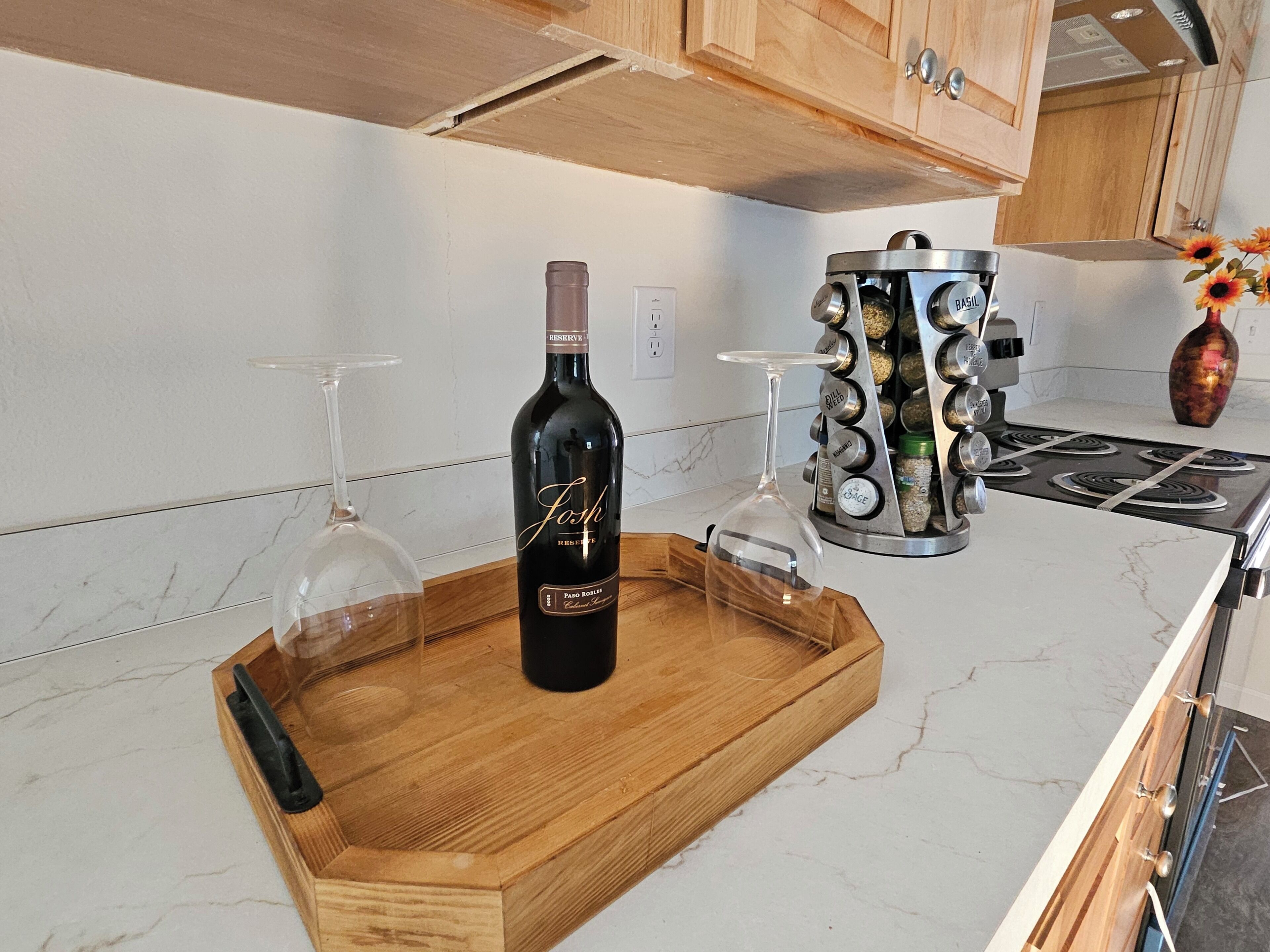 Una encimera de cocina con una botella de vino, una copa y una especiero.