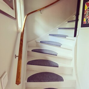 A white staircase with dark carpeted steps and a wooden handrail. - Vacation home in the idyllic village of Bolmen, 500 meters from Lake Bolmen (Ljungby)