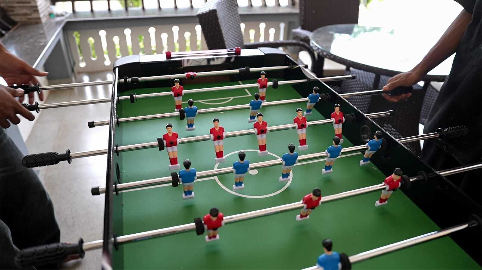 A tabletop foosball table with players in red and blue uniforms.