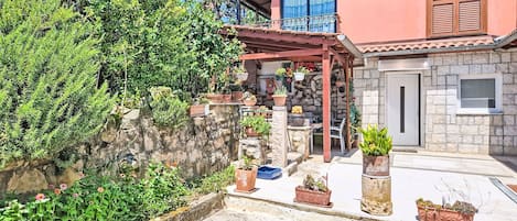 A house with a stone facade, a balcony with potted plants, and a clear sky.