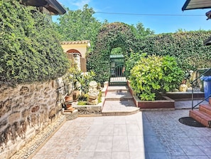 A stone pathway leading to a gate, surrounded by greenery and a small building with a tiled roof. - Apartment Monte by Interhome (Umag)