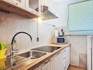 A modern kitchen with stainless steel appliances, a double sink, and wooden cabinetry. - Apartment Monte by Interhome (Umag)