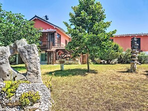 A building with a red facade, a stone pathway, and a tree in the foreground. - Apartment Monte by Interhome (Umag)