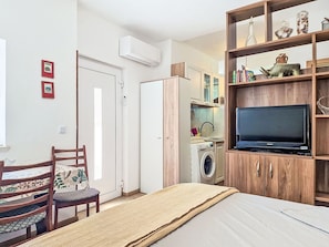 A bedroom with a bed, a TV on a wooden stand, a washing machine, and a chair. - Apartment Monte by Interhome (Umag)