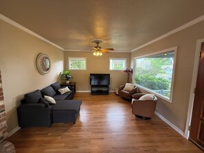 A living room with a sofa, chairs, a TV, and a ceiling fan. - Welcome to Harley's House - A cozy 3bed/2bath home in the heart of Enumclaw (Enumclaw)