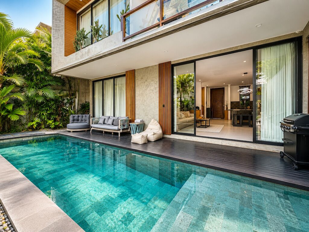 A modern house with a swimming pool, a dining area, and a living room with a sofa and chairs.