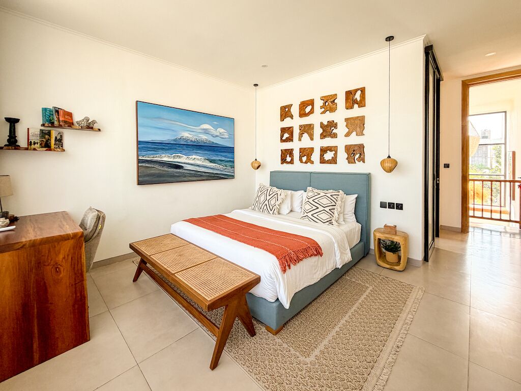 A bedroom with a bed, bedside table, and a desk.