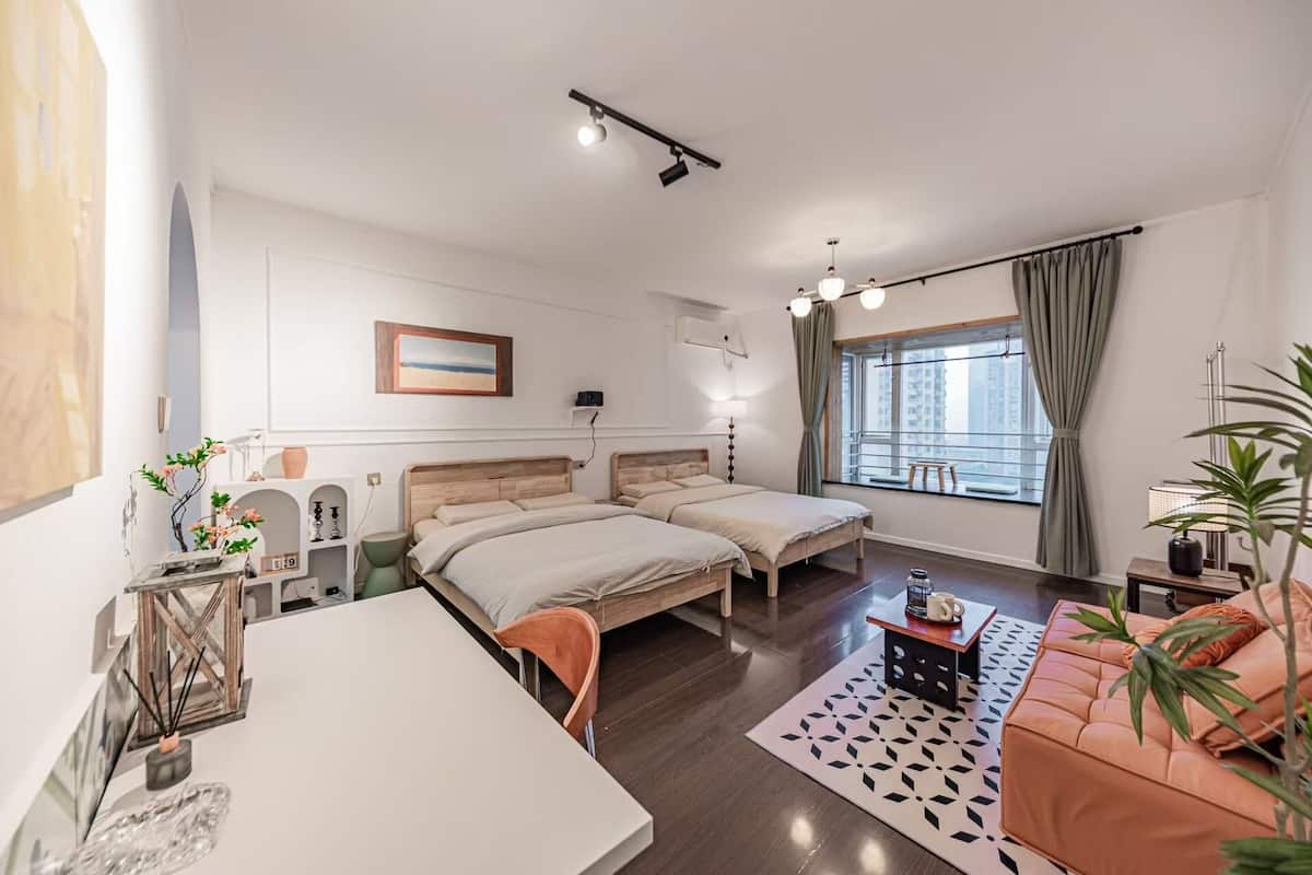 Un dormitorio moderno con dos camas, un escritorio, una mesa de centro y un sofá.