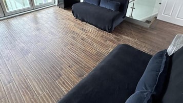 Un salon moderne avec un canapé, une petite table et une vue dégagée grâce à de grandes fenêtres.