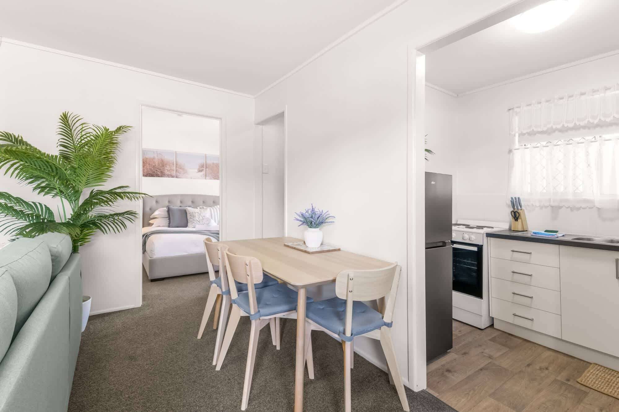 A compact living space with a dining area, kitchenette, and a bedroom with a large window.