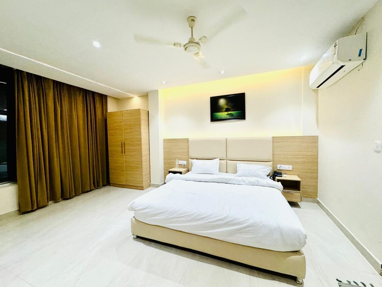 Une chambre d’hôtel moderne dotée d’un grand lit, d’un ventilateur de plafond, d’un climatiseur et d’une table de chevet avec une lampe.