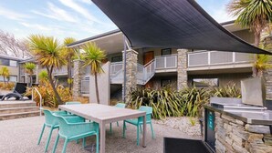 An outdoor patio area with a table and chairs, a grill, and a stone wall. - Wanaka Club Wyndham Resort.  5th-17th September 12 nights Studio King Sleeps 3. (Wānaka)