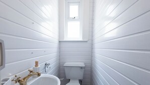 A small, white bathroom with a sink, toilet, and window. - The Bay Apart-Hotel by Guestz (Morecambe)