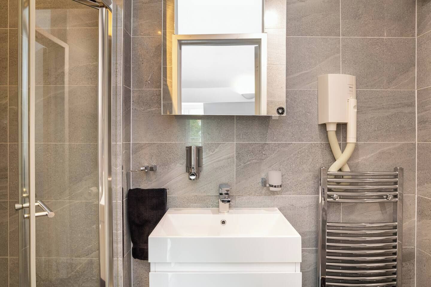 Une salle de bain moderne avec une douche à parois de verre, un lavabo blanc et un porte-serviettes.