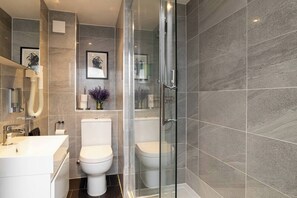 Une salle de bain moderne avec une douche à parois de verre, des toilettes blanches et un lavabo avec un miroir.