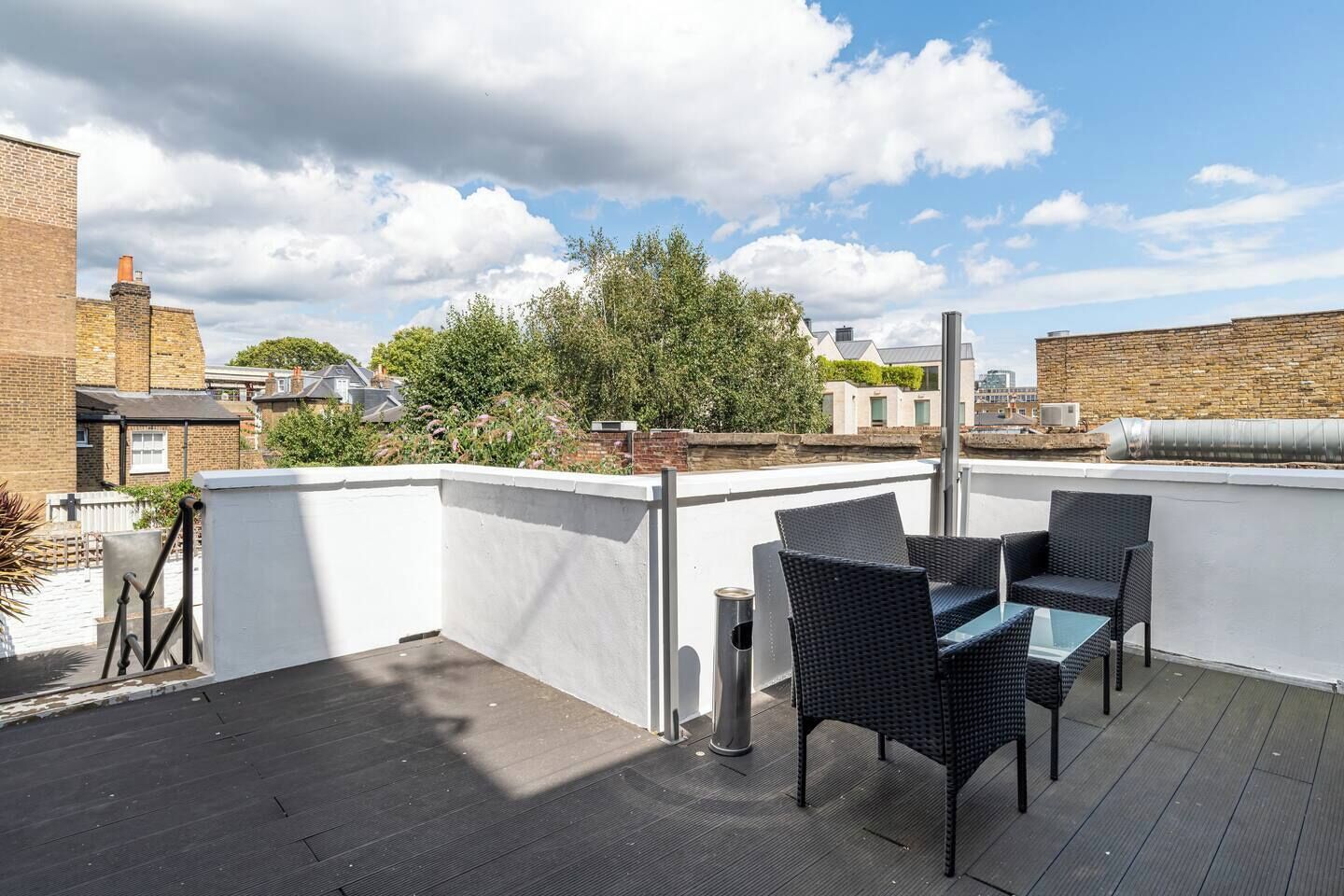 Terraço no telhado com mobiliário externo, vista da cidade e céu claro.