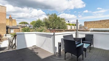 Une terrasse sur le toit, aménagée avec du mobilier d’extérieur, offrant une vue sur la ville et un ciel dégagé.