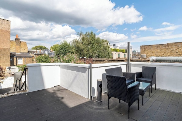 A rooftop terrace with outdoor furniture, a view of the city, and a clear sky. - 3 Bedroom ensuite Garden Flat in City min to Tube (Greater London)