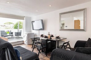 Un salon moderne comprenant un coin repas, un téléviseur à écran plat et un grand miroir.