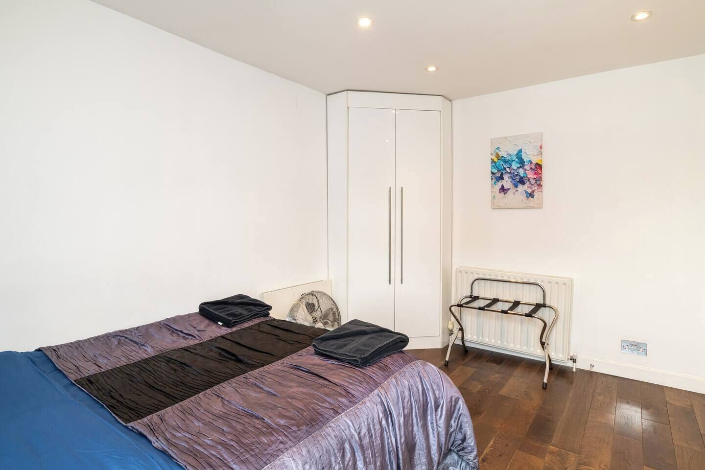 Une chambre à coucher comprenant un lit, un radiateur, une armoire et une œuvre d’art accrochée au mur.