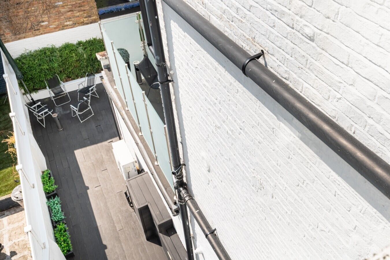 Eine Dachterrasse mit Sitzgelegenheiten im Freien und einer weißen Ziegelwand.