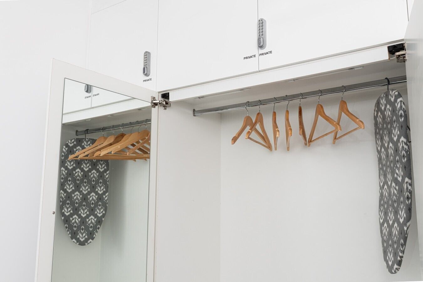 Ein Schrank mit Spiegel, Kleiderstange und Ablagefläche für Kleidungsstücke mit Muster.