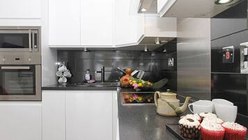 A modern kitchen with stainless steel appliances, white cabinetry, and a black countertop.