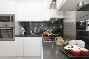 Une cuisine moderne dotée d’appareils électroménagers en acier inoxydable, de meubles blancs et d’un plan de travail noir.
