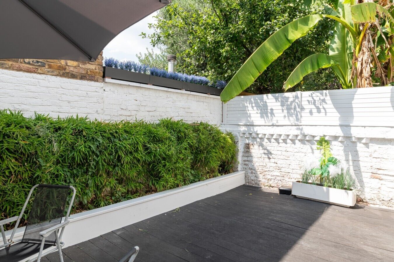 A covered patio area with a white brick wall, a black rubber floor, and a metal chair.