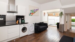 Una cucina moderna con elettrodomestici integrati, una lavatrice e un'area pranzo con un divano nero.
