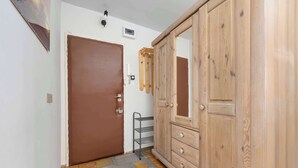 Una stanza con un'armadietto in legno, una porta, un piccolo ripiano e un tappeto.