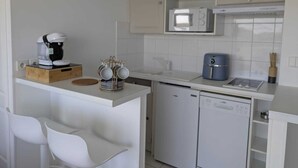 Eine kleine Küchenzeile mit Kaffeemaschine, Mikrowelle und Geschirrspüler.