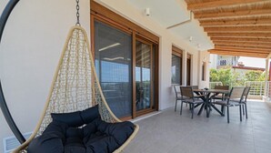 En hængestol med myggenet, et spisebord med stole og en skydedør til en balkon.