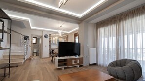 En moderne stue med et fladskærms-tv, en sofa og en trappe.
